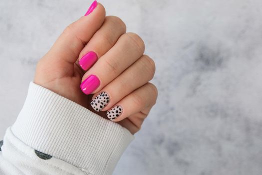 Manicured female hands with stylish pink nails and design. Trendy modern design manicure. Gel nails. Skin care. Beauty treatment. Nail care. Wellness. Trendy colors.