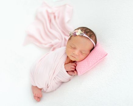 newborn baby girl sleeping sweetly on a little pillow