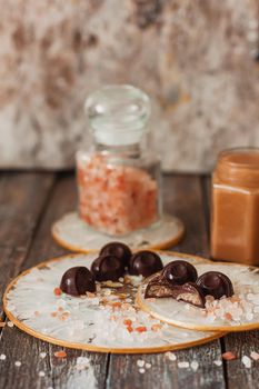 Homemade chocolate candies with salted caramel sauce on vintage background.