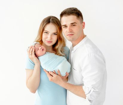 young beautiful parents holding a newborn daughter. white background