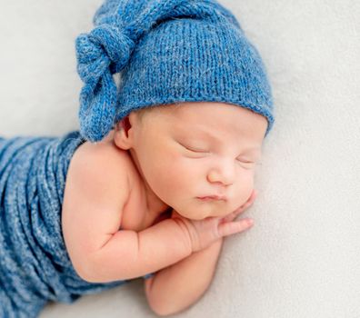 A little boy in a blue suit is sleeping with his hands behind his face