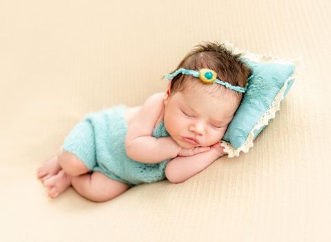 newborn baby girl sleeping sweetly on a little pillow