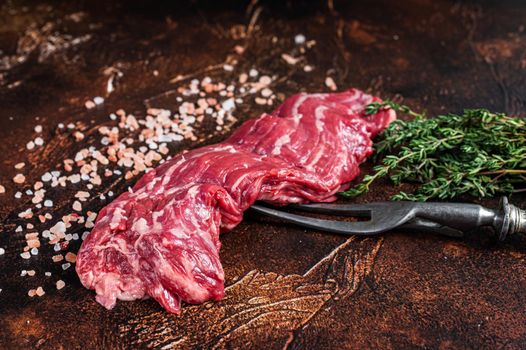 Raw machete skirt beef steak on meat fork. Dark background. Top view.
