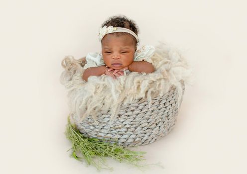 Lovely African newborn baby girl sitting in basket