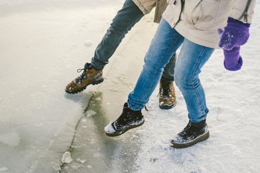 Trying the danger of the foot, testing the thin ice near the shore. A pair of lovers walk with a walk along a frozen lake to press foot on the ice.
