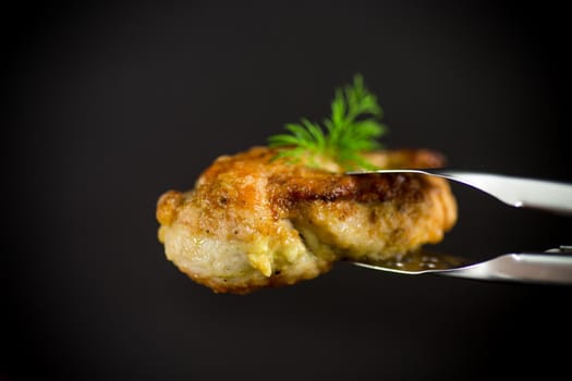a piece of fried chicken fillet with spices on a black background