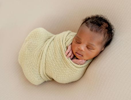 Adorable sleeping African newborn baby swaddled in sheet