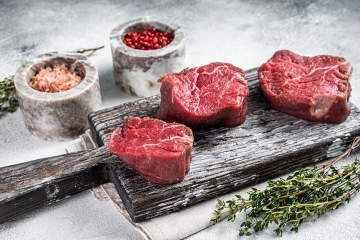 Fillet mignon beef raw steaks on a wooden board with salt and pepper. White background. Top view.