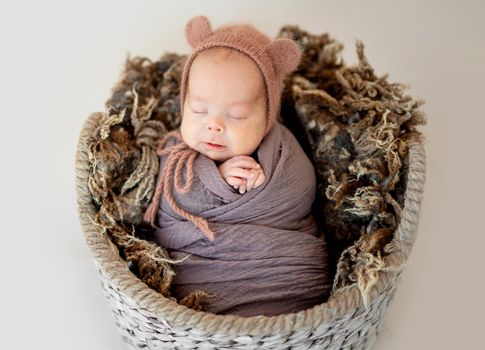 Lovely newborn wearing knitted hat in basket