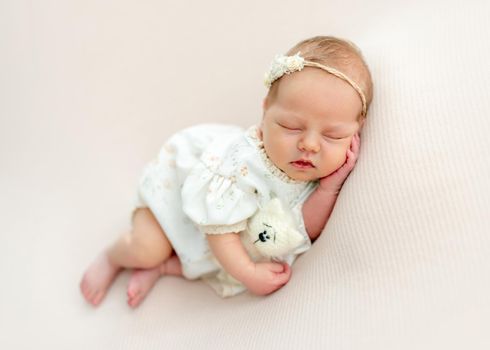 Sweet newborn baby hugging toy while sleeping