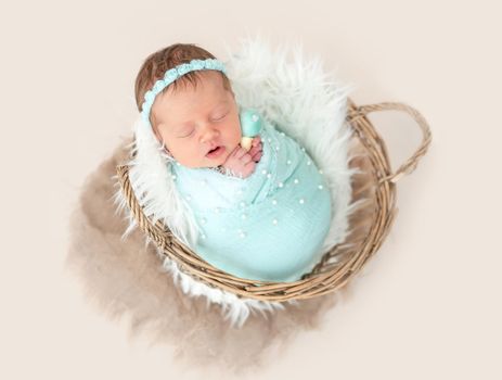 Adorable wrapped up newborn lying in basket