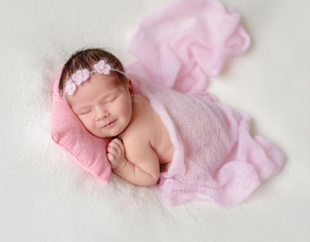 Cute sleeping newborn baby girl in a pink