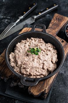 Duck pate Rillettes de Canard in a pan with greens. Black background. Top View.