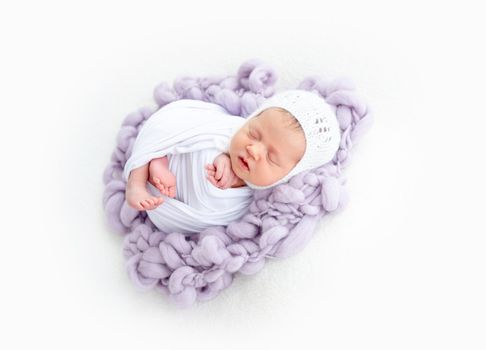 Charming newborn in white knitted hat sleeping