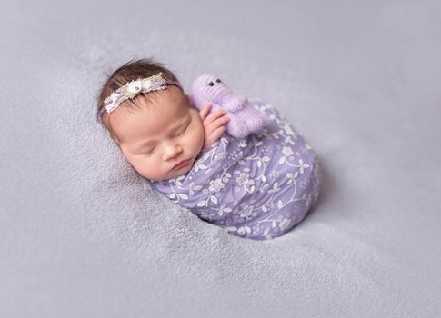 Cute sleeping newborn baby girl in violet