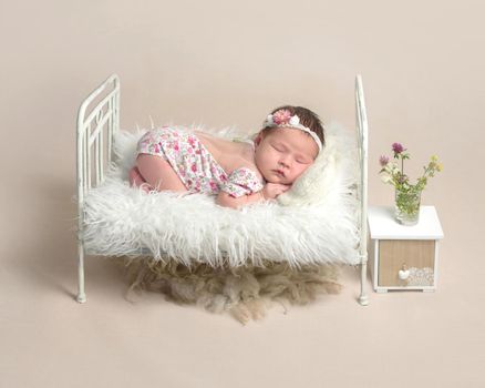 Cute sleeping newborn baby girl in the little bed