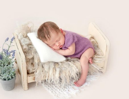 Funny newborn sleeping in tiny bed