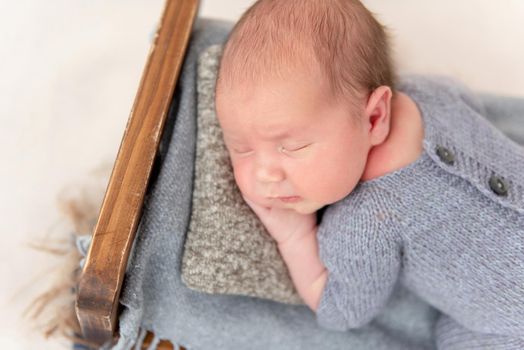 Funny newborn sleeping comfortably on tiny bed