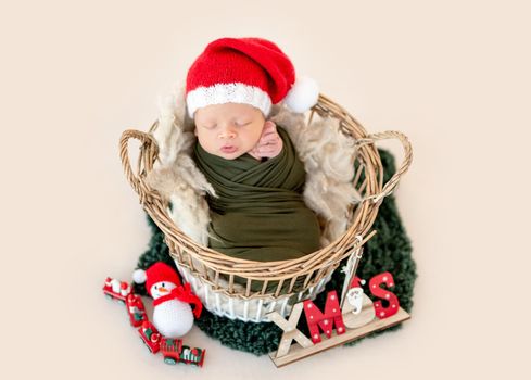 Adorable newborn in christmas hat sleeping in basket