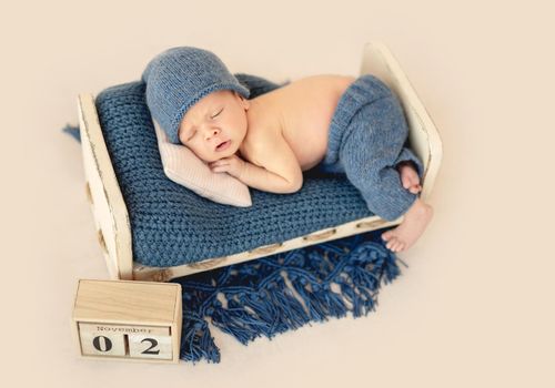 Charming newborn in cute hat sleeping on tiny pillow