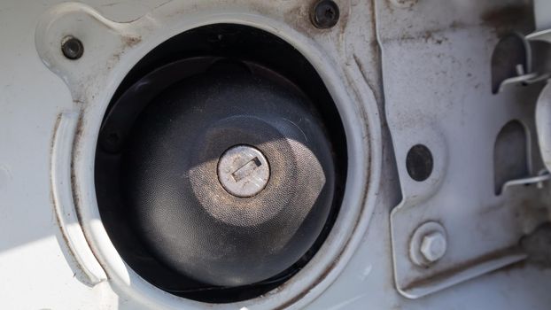 Fuel cap of a white sports car. Close the gas tank cap. The fuel tank is open. The fuel filler door is open and the fuel filler flap is closed. The exterior of the car with the filler door open