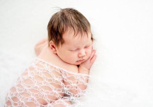 Beautiful newborn covered with openwork knitted blanket