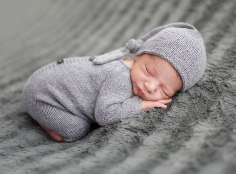 Sweet newborn in grey suit sleeping on stomach