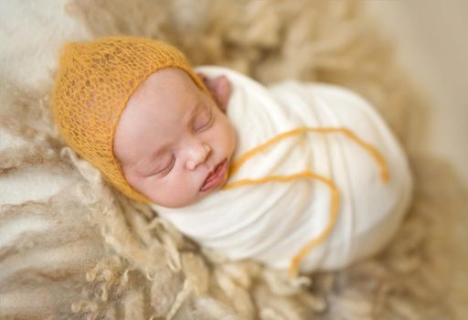 Little cute baby covered with white coverlet sweetly sleeping on woolen blanket