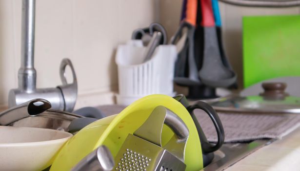 The kitchen utensils in the wash basin need to be washed. A pile of dirty dishes in the kitchen sink. Kitchen utensils need washing. Homework concept