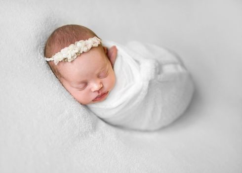 Little cute baby covered with white coverlet sweetly sleeping on woolen blanket