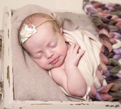 Cute little baby in knitted brown suit sweetly sleeping on the woolen blanket in little bed