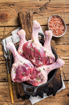 Raw Duck drumsticks in a pan with herbs. wooden background. Top view.