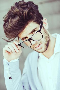 Portrait of cheerful trendy guy with black eyeglasses on