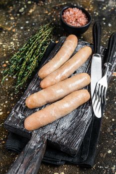 Grilled chicken sausages on a wooden board. Brown background. Top view.