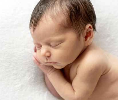 Just a few days old baby sleeping on tummy. Sleeping newborn child curled up. Beginning of a new life concept