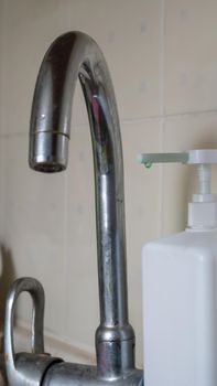 Old tall mixer in the kitchen with a dispenser of liquid soap for washing dishes, close-up. Vertical photography
