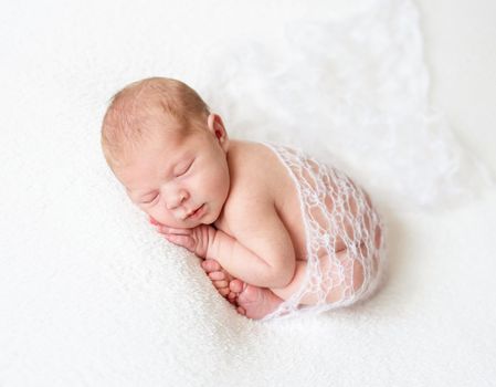 A sleeping baby boy on lace fabric, isolated on white background