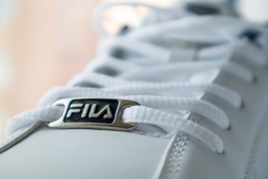 White athletic lace-up sneakers. White laces are tied close-up. Blurred background. Sports concept. Famous brand logo Fila. Fashionable and stylish footwear. Ukraine, Kiev - June 17, 2021
