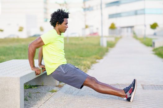 Black man doing triceps dip exercise on city street bench. Fitness, sport, exercising, training and people concept