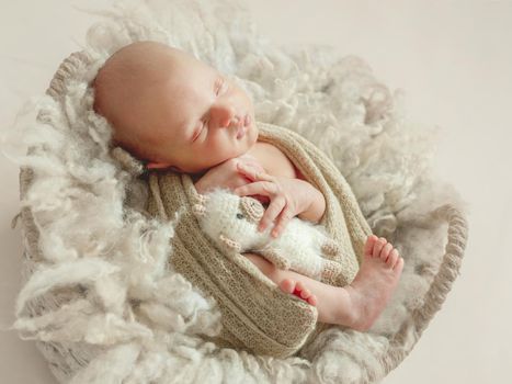 Adorable newborn child sleeping on fluffy wool blanket in little knitted hat