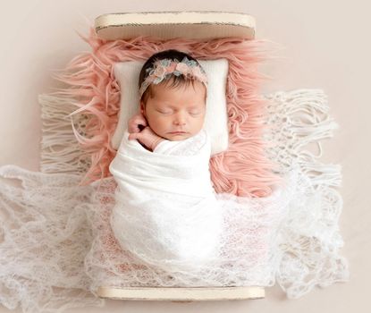 Little cutie infant girl sleeping on baby bed