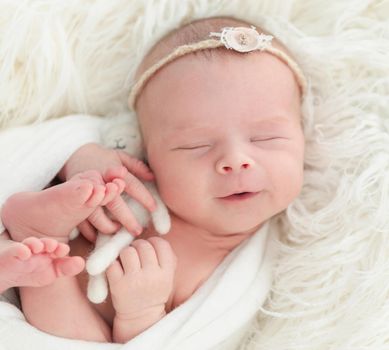 smiling newborn baby girl sleeping sweetly with a small toy