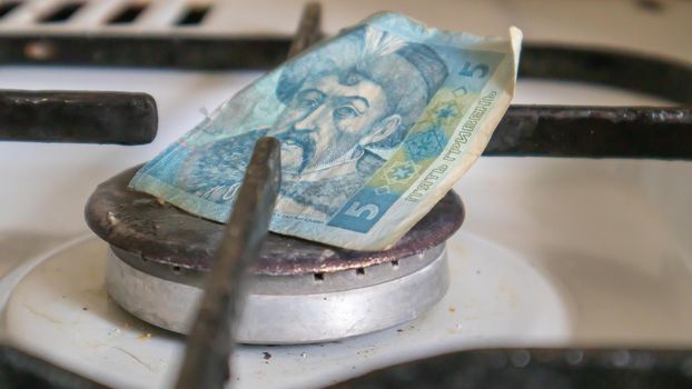 Ukrainian hryvnia on a gas water heater without fire. Gas stove with money. Conceptual image of a rising tariff for violence. Natural gas saving concept at home, high gas prices