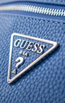 Blue Leather Shoulder Bag by GUESS. Triangular metal logo close-up. Ukraine, Kiev - June 17, 2021