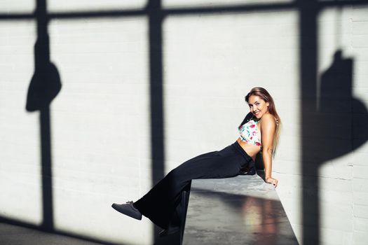 Funny young girl sitting on urban wall outdoors