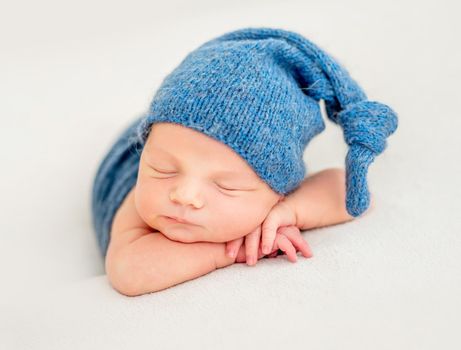 A little boy in a blue suit is sleeping with his hands behind his face