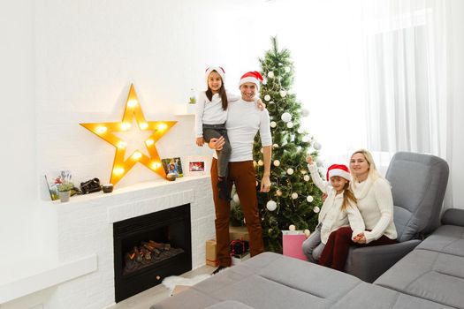 happy family father mother and children sitting by fireplace on Christmas Eve