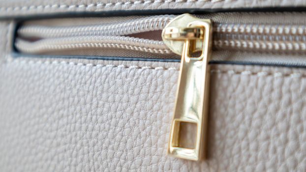 Natural or artificial leather texture. Fragment of a beige or powdery bag with a zipper and stitching. Zipper or clasp bag design element. Bovine skin texture with snake. Macro photo, selective focus