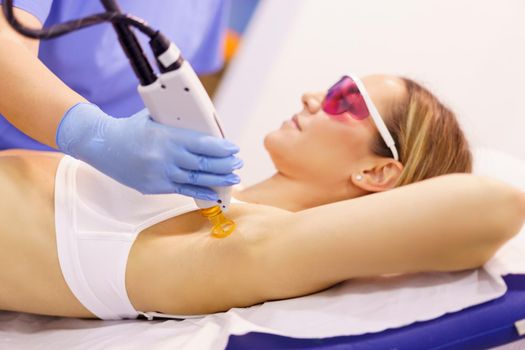 Woman receiving underarm laser hair removal at a beauty center. Laser depilation treatment in an aesthetic clinic.