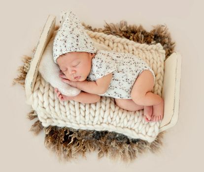 Dreamy newborn baby sleeping peacefully on the side on bed